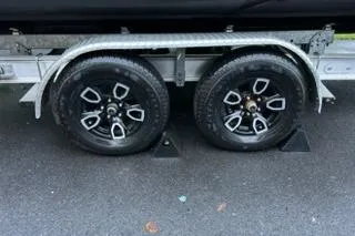Slide: The Image of Trailer wheels of a 2023 NauticStar 24 Legacy boat on asphalt. - 18