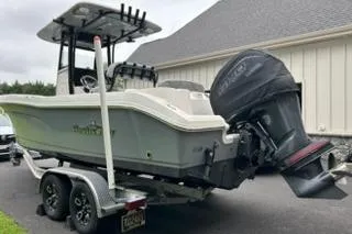 Slide: The Image of 2023 NauticStar 24 Legacy boat on trailer, parked near a building. - 2