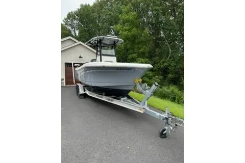 Slide: The Image of 2023 NauticStar 24 Legacy boat on trailer, parked in driveway near trees. - 4