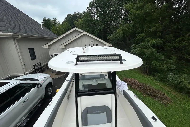 Slide: The Image of 2023 NauticStar 24 Legacy boat parked near a house, surrounded by greenery. - 6