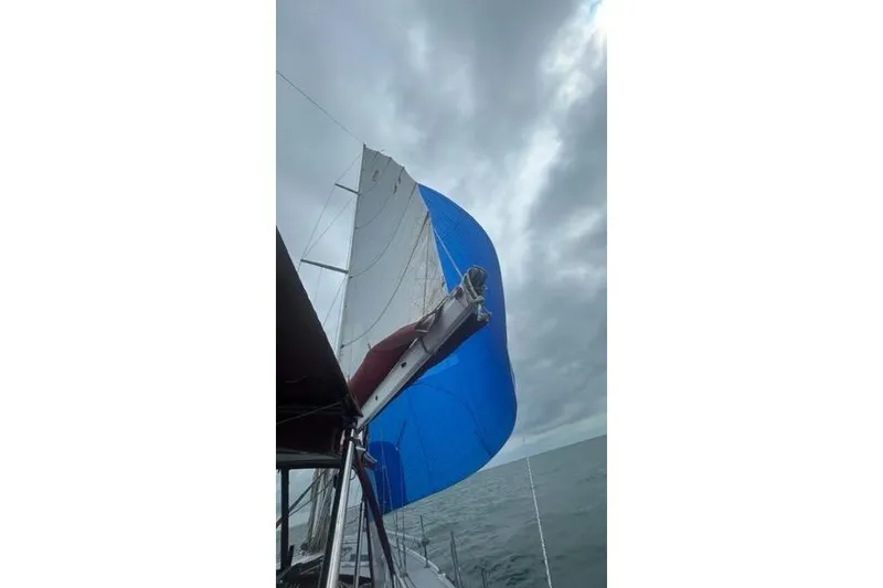 Slide: The Image of Sailing on a 1998 Catalina 42 with blue spinnaker under cloudy skies. - 12
