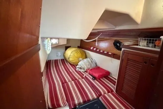 Slide: The Image of 1998 Catalina 42 sailboat cabin with striped cushions and storage. - 23