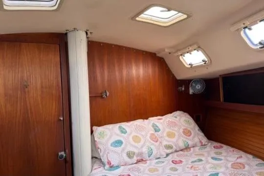 Slide: The Image of Interior cabin of a 1998 Catalina 42 sailboat with cozy bedding and wooden paneling. - 29