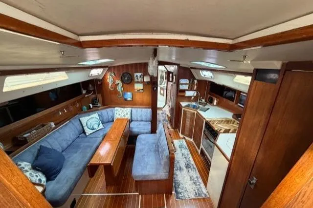 Slide: The Image of 1998 Catalina 42 yacht interior with blue seating, wooden finishes, and a compact kitchen area. - 38