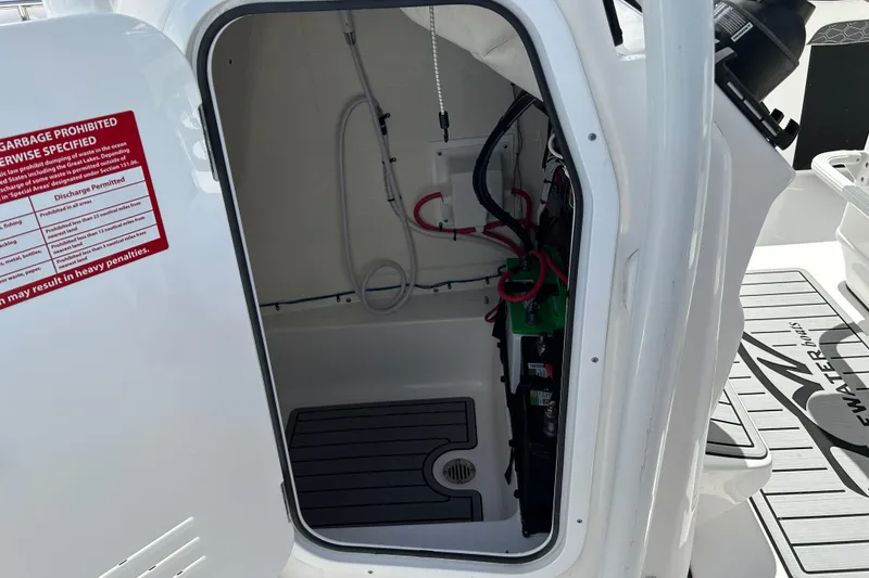 Slide: The Image of 2024 Tidewater 220 LXF boat storage compartment with wiring and battery setup. - 15
