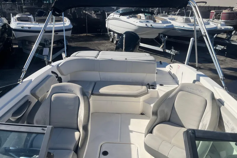 Slide: The Image of 2020 Sea Ray SPX 210 boat interior with seating and canopy, docked among other boats. - 11