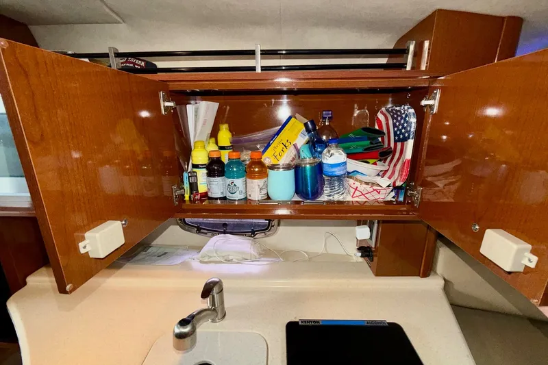 Slide: The Image of Cabinet interior on 2012 Sea Ray Sundancer 280, stocked with beverages and essentials. - 33