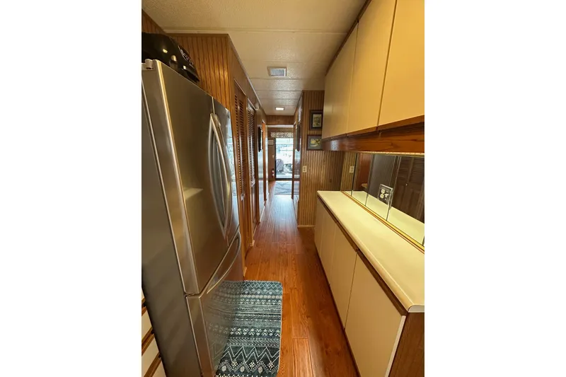 Slide: The Image of Narrow kitchen in 1993 Sumerset 14x65 houseboat with wood paneling and stainless steel fridge. - 6