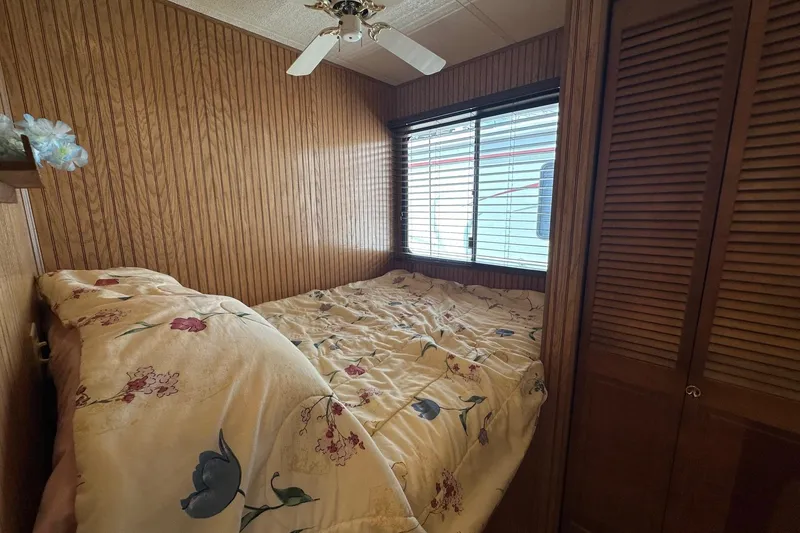Slide: The Image of Cozy bedroom in 1993 Sumerset 14x65 houseboat with floral bedding and wood paneling. - 7