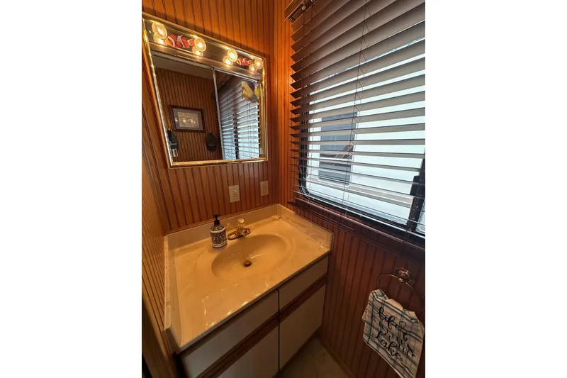 Slide: The Image of Bathroom vanity in 1993 Sumerset 14x65 houseboat with wood paneling and blinds. - 9