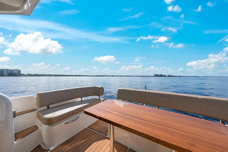 Slide: The Image of 2016 Carver C37 Coupe yacht deck with seating and table, overlooking serene water and blue sky. - 18