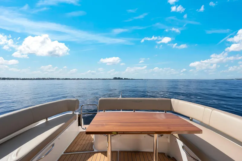 Slide: The Image of 2016 Carver C37 Coupe yacht deck with table, overlooking serene ocean and blue sky. - 19