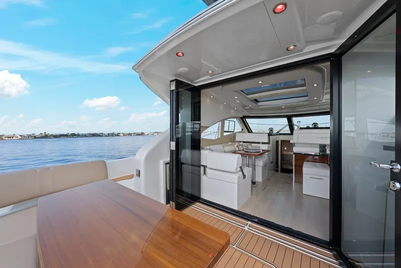 Slide: The Image of 2016 Carver C37 Coupe yacht interior with open deck, wooden table, and scenic water view. - 26