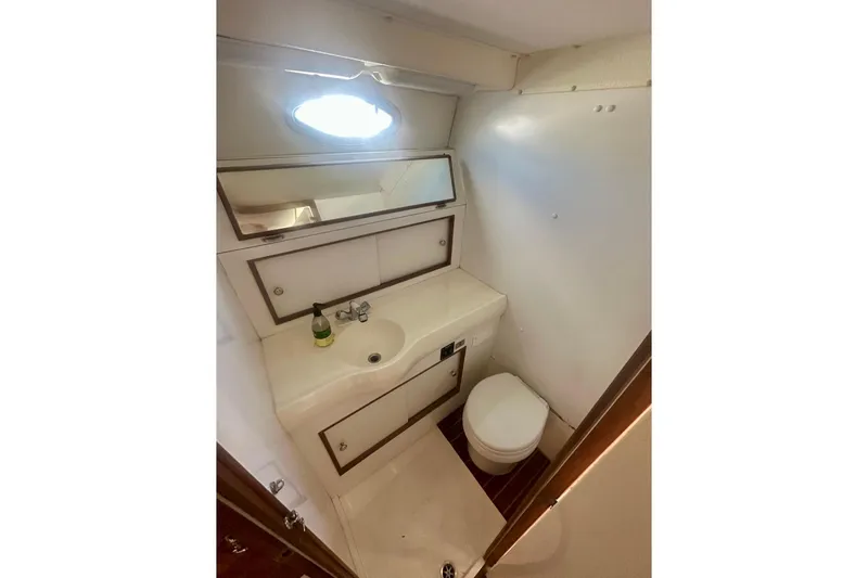 Slide: The Image of 1985 Bertram 28 Bahia Mar boat bathroom with sink, mirror, and toilet. - 6