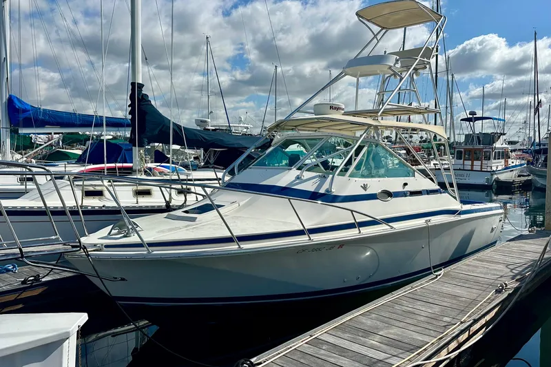 Slide: The Image of 1985 Bertram 28 Bahia Mar boat docked at a marina under a partly cloudy sky. - 7