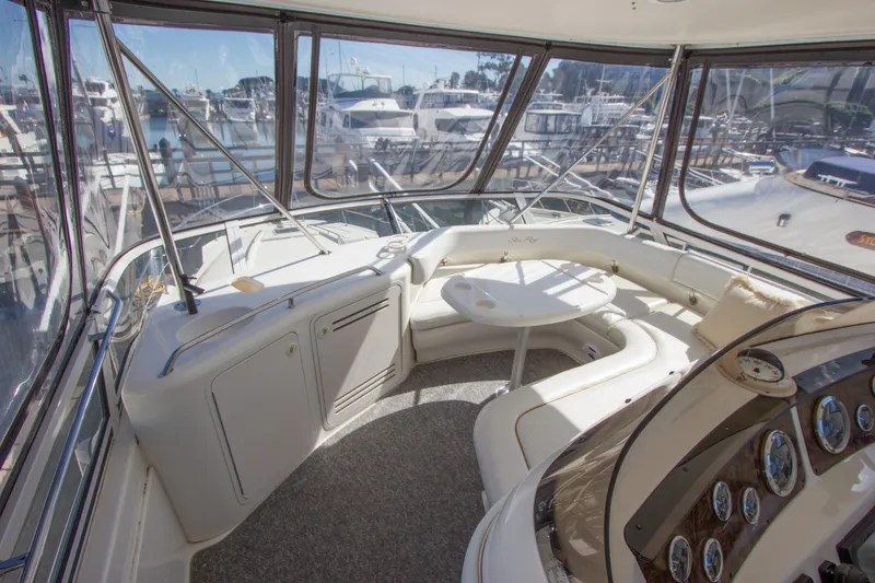 Slide: The Image of 1998 Sea Ray 480 Sedan Bridge interior with seating and helm, overlooking marina. - 32
