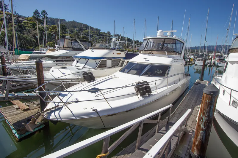 Slide: The Image of 1998 Sea Ray 480 Sedan Bridge yacht docked in a marina under clear blue skies. - 6