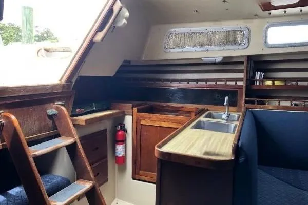 Slide: The Image of Interior of a 1981 Catalina 30 sailboat with wooden cabinetry and compact kitchen area. - 11