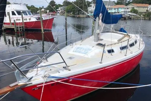 Slide: The Image of 1981 Catalina 30 sailboat with red hull docked in a marina. - 2