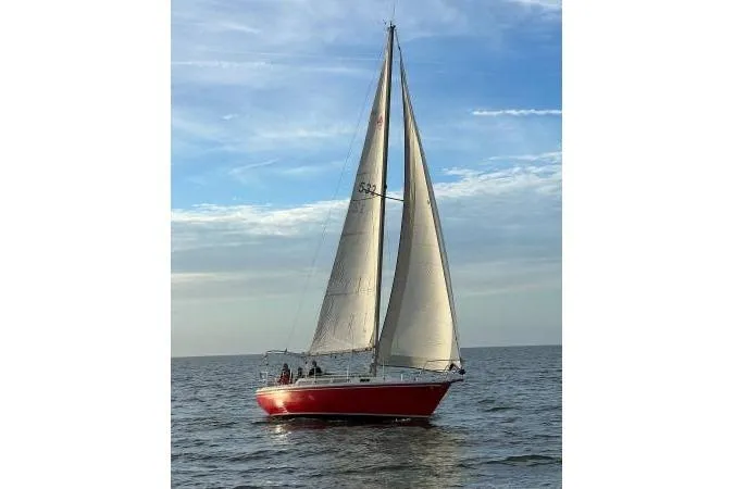 Slide: The Image of 1981 Catalina 30 sailboat with red hull sailing on open water under blue sky. - 3