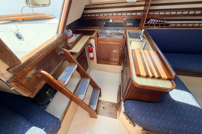 Slide: The Image of Wooden cabinet with open doors revealing storage inside a 1981 Catalina 30 sailboat. - 49