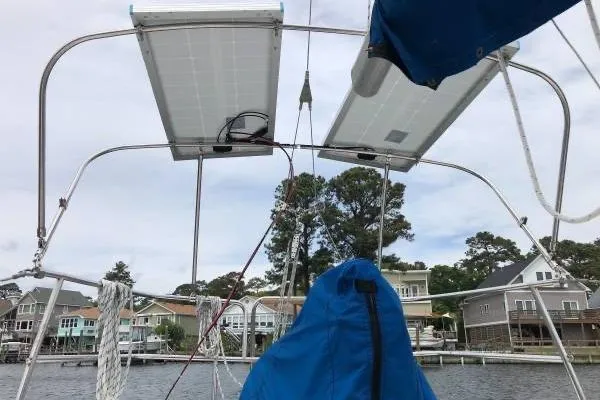 Slide: The Image of 1981 Catalina 30 sailboat with solar panels, docked near waterfront homes. - 5