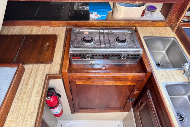 Slide: The Image of 1981 Catalina 30 yacht kitchen with stove, sink, and wooden cabinetry. - 6