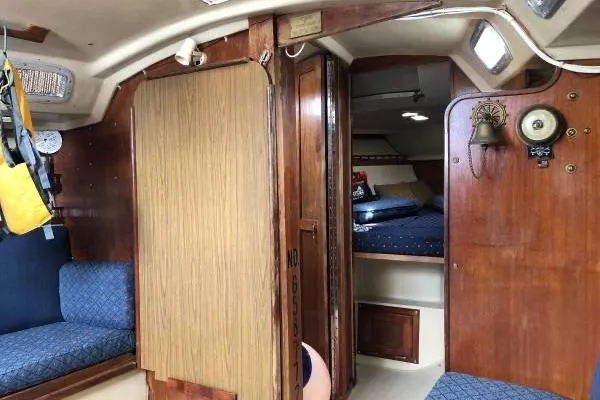 Slide: The Image of Interior of a 1981 Catalina 30 sailboat with wood paneling and blue seating. - 8