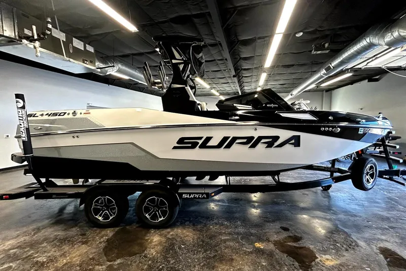 The Image of 2023 Supra SA 450 boat in showroom, sleek design, black and white color scheme. - 0