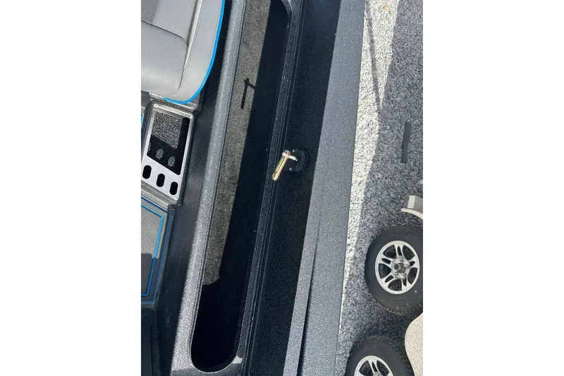 Slide: The Image of 2026 Xpress XR21 Bass boat interior with storage compartment and trailer wheels visible. - 13