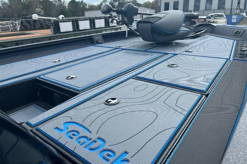 Slide: The Image of 2026 Xpress XR21 Bass boat deck with SeaDek flooring, featuring blue accents and storage compartments. - 17