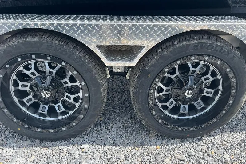 Slide: The Image of 2026 Xpress XR21 Bass trailer wheels with stylish black alloy rims on gravel. - 6