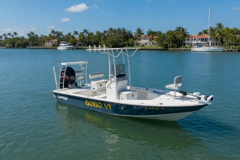 The Image of 2021 Mako 21 LTS boat named "BOBO VI" on calm water, with scenic waterfront homes. - 0