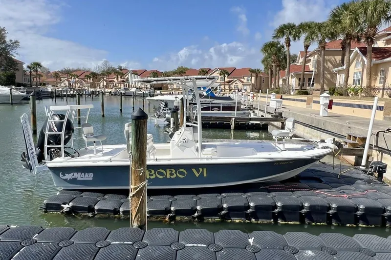 Slide: The Image of 2021 Mako 21 LTS boat docked in a sunny marina with palm trees. - 14