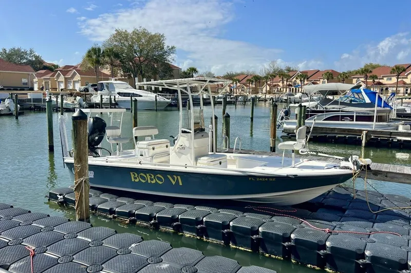 Slide: The Image of 2021 Mako 21 LTS boat docked in a marina with residential backdrop. - 15