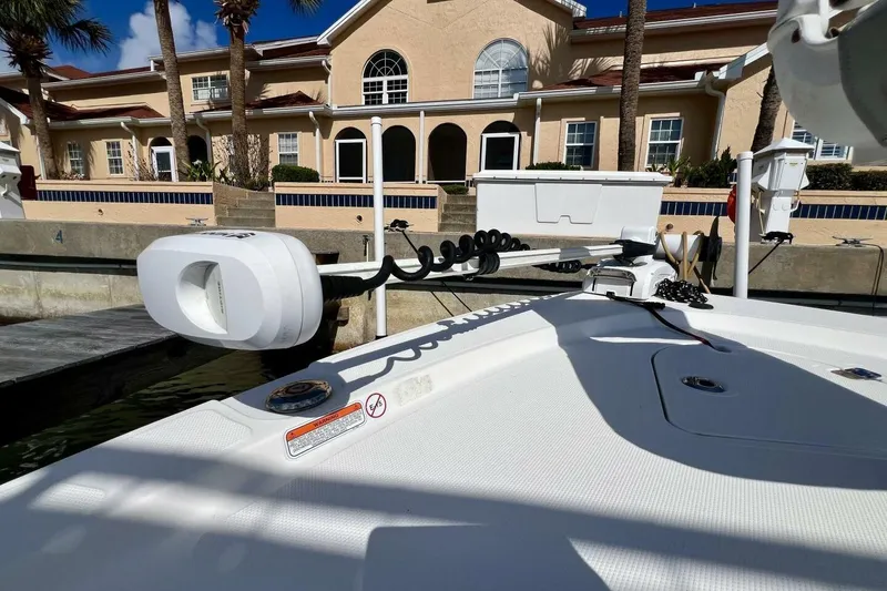 Slide: The Image of 2021 Mako 21 LTS boat docked near a waterfront building under clear skies. - 21