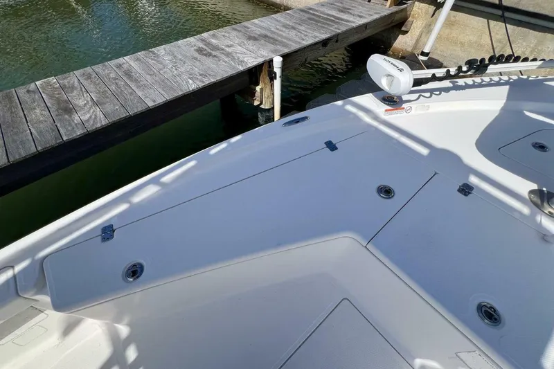 Slide: The Image of 2021 Mako 21 LTS boat deck near wooden dock, featuring storage compartments. - 23