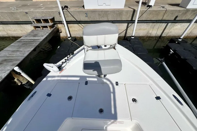 Slide: The Image of 2021 Mako 21 LTS boat with a cushioned seat docked at a marina. - 24