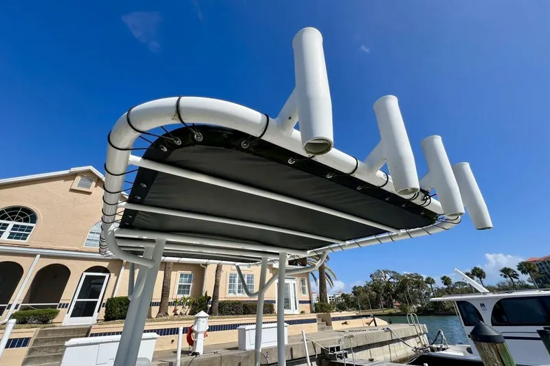 Slide: The Image of 2021 Mako 21 LTS boat T-top with rod holders, docked under clear blue sky. - 31