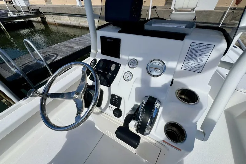 Slide: The Image of 2021 Mako 21 LTS boat console with steering wheel and gauges at dock. - 33