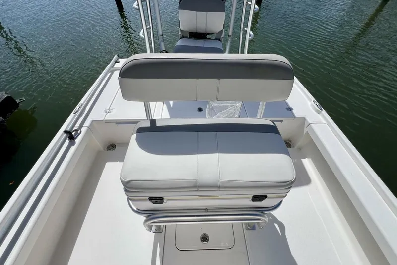 Slide: The Image of 2021 Mako 21 LTS boat interior with cushioned seating and storage, on calm water. - 39