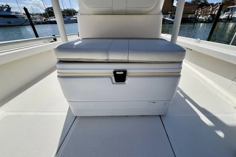 Slide: The Image of 2021 Mako 21 LTS boat interior with cushioned cooler seat, docked at marina. - 9