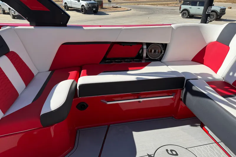 Slide: The Image of 2022 MasterCraft X26 boat interior with red and white seating, cup holders, and speaker system. - 13