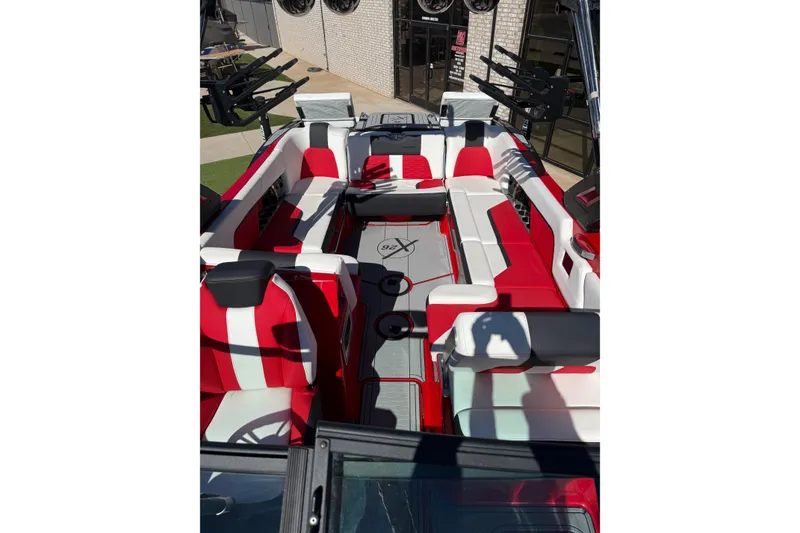 Slide: The Image of 2022 MasterCraft X26 boat interior with red and white seating, docked outdoors. - 17