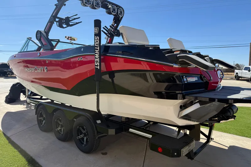 Slide: The Image of 2022 MasterCraft X26 boat on trailer, red and black design, parked outdoors. - 20