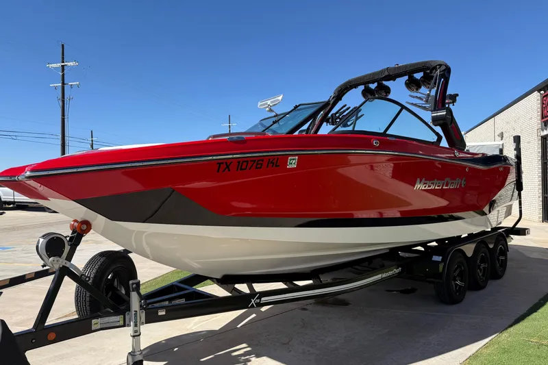 Slide: The Image of 2022 MasterCraft X26 boat in vibrant red on a trailer, parked outdoors. - 3