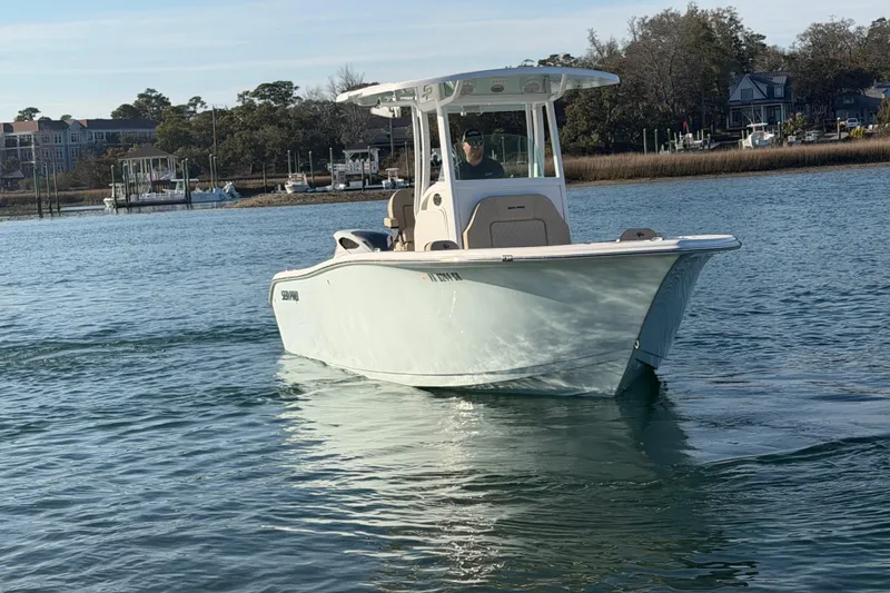Slide: The Image of 2023 Sea Pro 239 Center Console boat cruising on calm water near shoreline. - 16