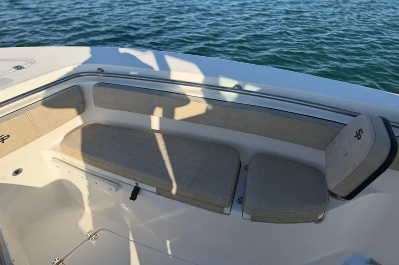 Slide: The Image of 2023 Sea Pro 239 Center Console boat seating area with beige cushions on calm water. - 42