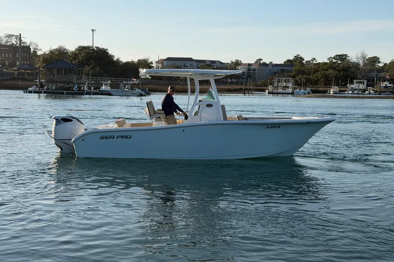 Slide: The Image of 2023 Sea Pro 239 Center Console boat cruising on calm waters near a marina. - 6