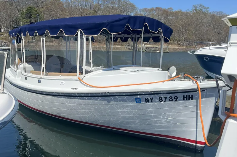 The Image of 2021 Duffy Cuddy Cabin 22 boat docked with blue canopy and registration number visible. - 1